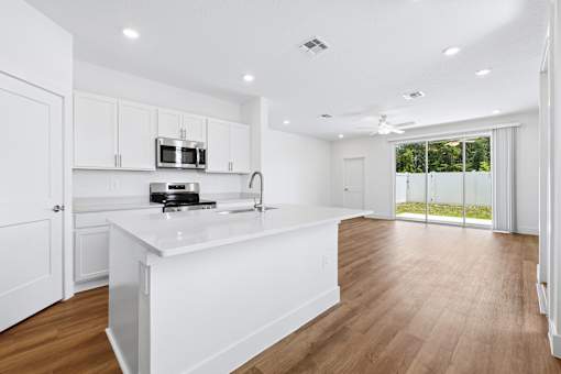 A kitchen with white cabinets and a white island.