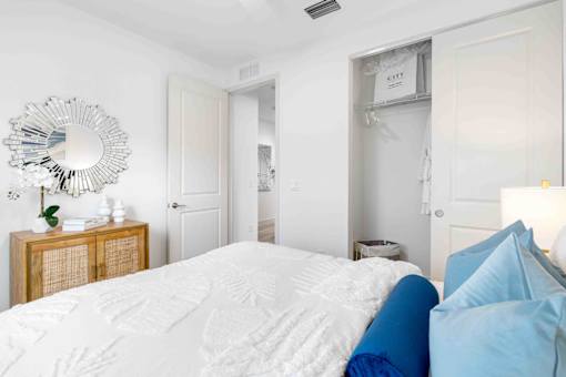 a white bedroom with a bed and a mirror