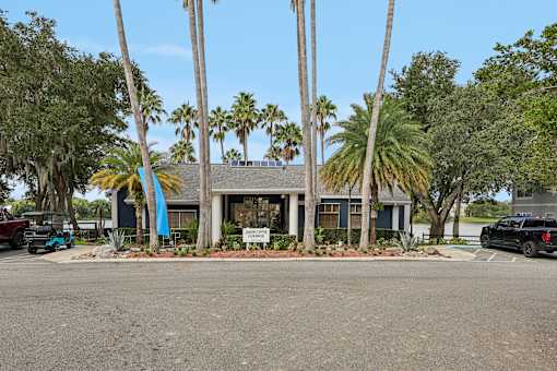 A building with a sign in front of it surrounded by palm trees.