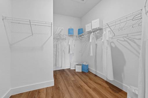 A white room with clothes hanging on racks and a blue box on the floor.