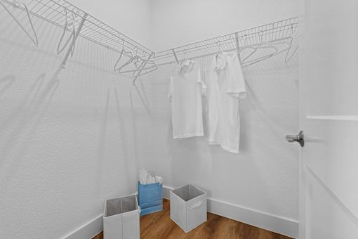 A laundry room with clothes hanging on a rack and baskets on the floor.