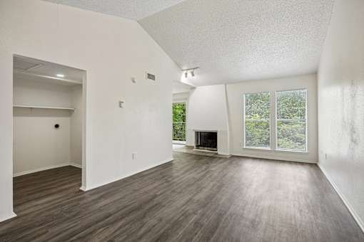 A large empty room with wood flooring and a fireplace.