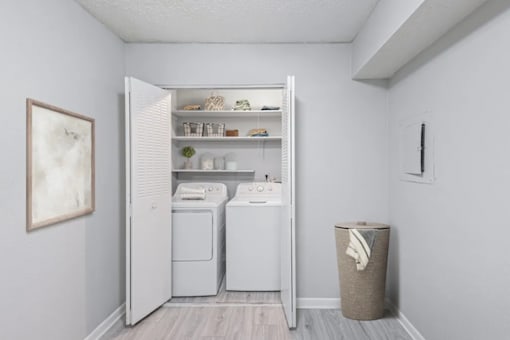 A laundry room with a washer and dryer and a trash can.