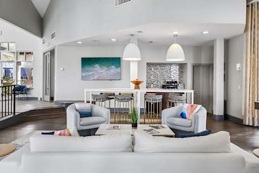 A modern living room with a white couch and a painting of a wave on the wall.