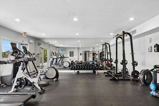 A gym with a variety of equipment including treadmills, weights, and exercise machines.