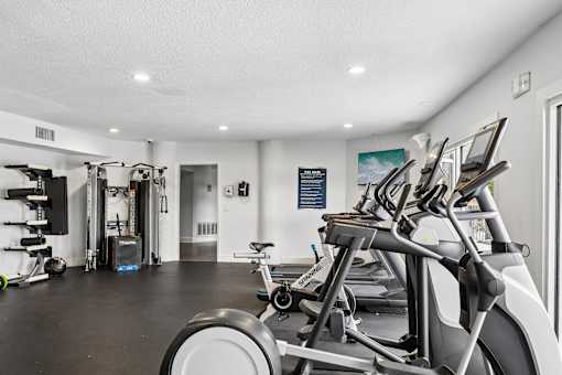 A gym with a row of stationary bikes and other exercise equipment.