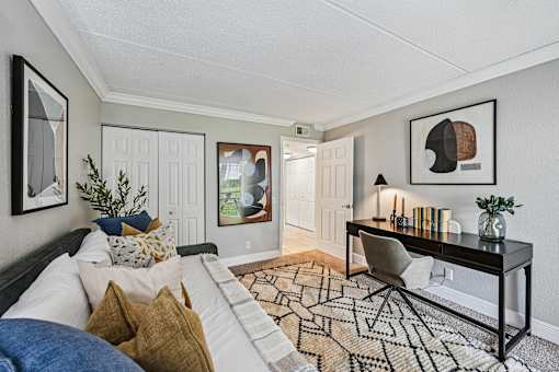 A living room with a black and white patterned rug, a white sofa, a black coffee table, and a framed picture on the wall.