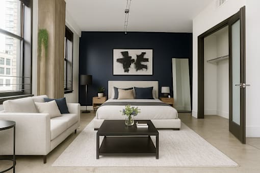 A modern living room with a white sofa, a black coffee table, and a large abstract painting on the wall.