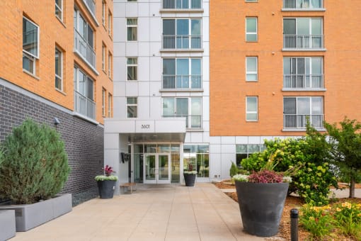 the entrance to an apartment building with a walkway and plants at Verge Apartments in St. Louis Park, MN