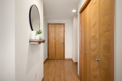 a hallway with a wooden door and a mirror on the wall at Verge Apartments in St. Louis Park, MN