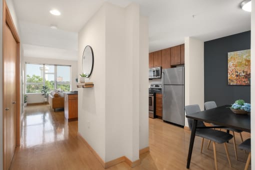 a dining room with a table and chairs and a kitchen with stainless steel appliances at Verge Apartments in St. Louis Park, MN