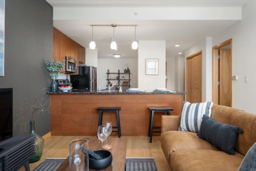 a living room with a couch and a kitchen with a bar at Verge Apartments in St. Louis Park, MN
