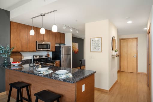a kitchen with a granite counter top and a stainless steel refrigerator at Verge Apartments in St. Louis Park, MN