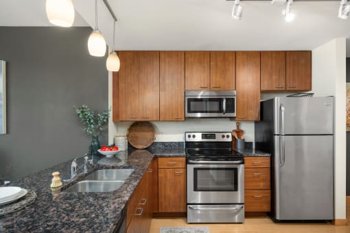 a kitchen with granite counter tops and stainless steel appliances at Verge Apartments in St. Louis Park, MN