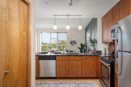 a kitchen with wooden cabinets and stainless steel appliances and a window at Verge Apartments in St. Louis Park, MN