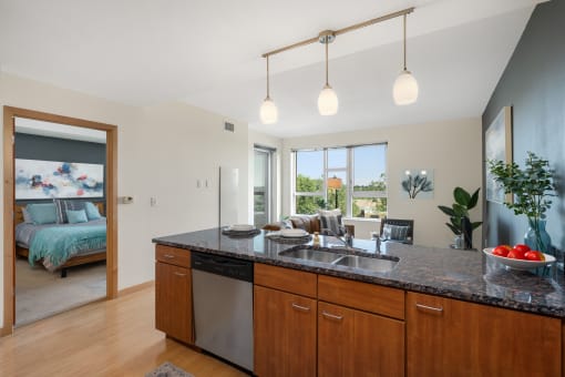 an open kitchen and living room with a bedroom in the background at Verge Apartments in St. Louis Park, MN