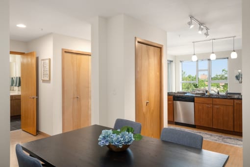 a dining room with a table and chairs and a kitchen at Verge Apartments in St. Louis Park, MN