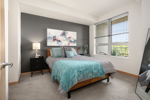 a bedroom with a bed and a large window at Verge Apartments in St. Louis Park, MN