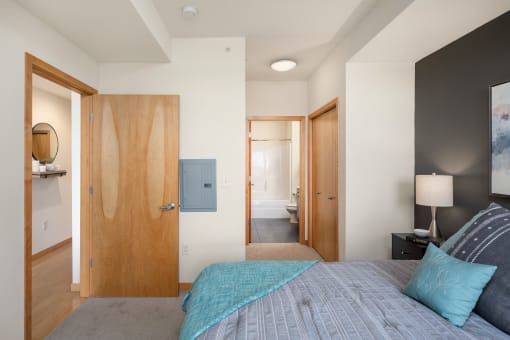 a bedroom with a bed and a door to a bathroom at Verge Apartments in St. Louis Park, MN