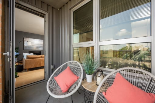 a porch with two chairs and a table and windows at Verge Apartments in St. Louis Park, MN