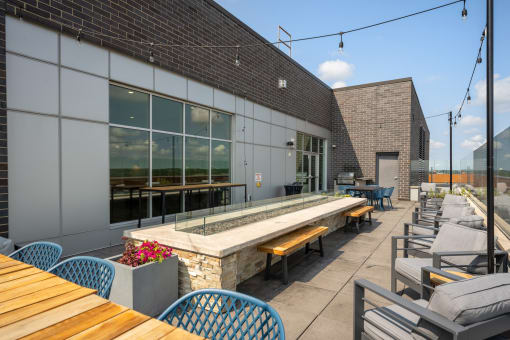 a patio with tables and chairs and a building with large windows at Verge Apartments in St. Louis Park, MN