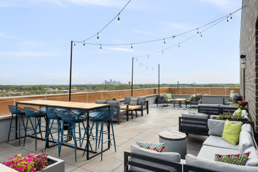 a rooftop patio with tables and chairs and a view of the city at Verge Apartments in St. Louis Park, MN