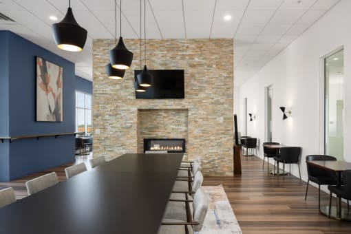 a dining room with a long table and chairs and a fireplace at Verge Apartments in St. Louis Park, MN