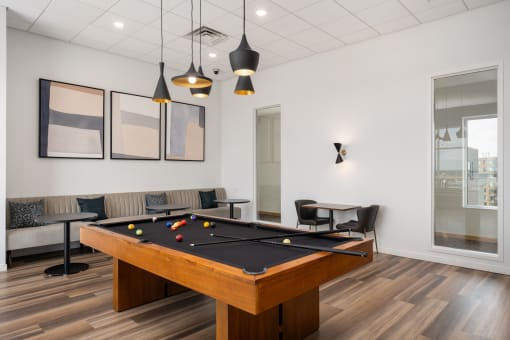 a billiards table in a game room with couches and tables at Verge Apartments in St. Louis Park, MN