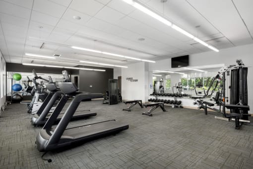 a gym with cardio equipment and weights in a building with white ceilings at Verge Apartments in St. Louis Park, MN