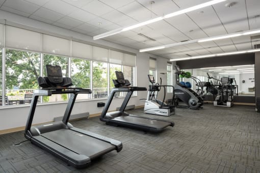 two treadmills and other exercise equipment in the fitness center of a building at Verge Apartments in St. Louis Park, MN