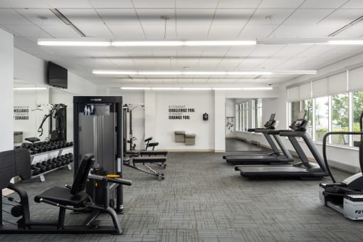 a gym with treadmills and other exercise equipment in a large room with windows at Verge Apartments in St. Louis Park, MN