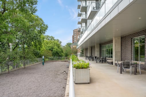 the terrace of a building with tables and chairs and trees at Verge Apartments in St. Louis Park, MN