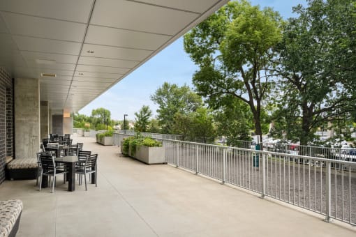 the terrace of the building has tables and chairs and a fenceat Verge Apartments in St. Louis Park, MN