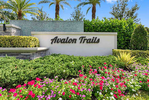 a sign that says avalon trails in front of flowers