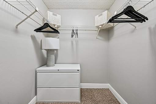 A white closet with a white dresser and a white shelf.