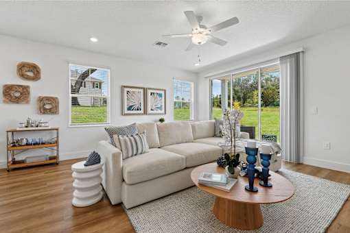 A living room with a white couch, a round coffee table, and a ceiling fan.