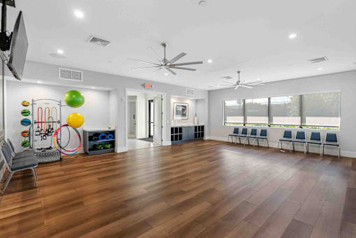a large room with hardwood floors and a gym with chairs and a large window