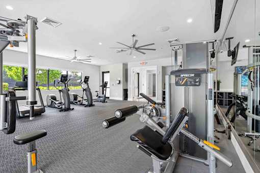 a gym with weights and cardio equipment in a building with windows