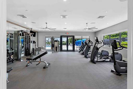 a gym with weights and cardio equipment in a building with glass doors