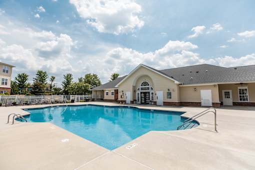 A large swimming pool in front of a building with a white exterior.
