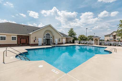 A large swimming pool in front of a building with a pool house.