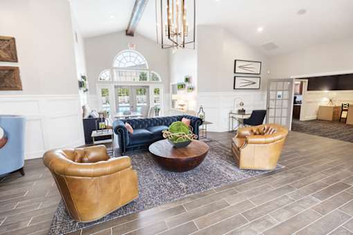 A living room with a blue couch, a brown leather chair, and a brown leather ottoman.