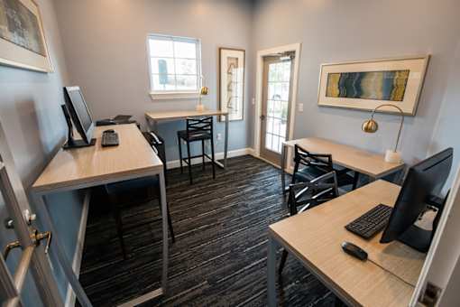 A room with two desks and chairs, one of which has a computer on it.