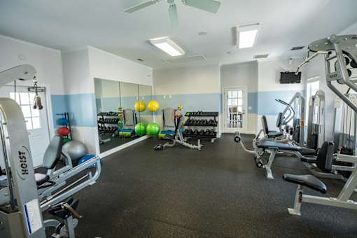 A gym with a variety of equipment including a weight bench, a leg press machine, and a treadmill.