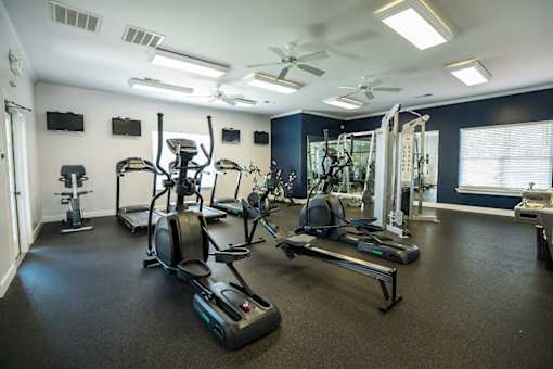 A spacious gym with a variety of equipment including treadmills, elliptical machines, and a weight bench.