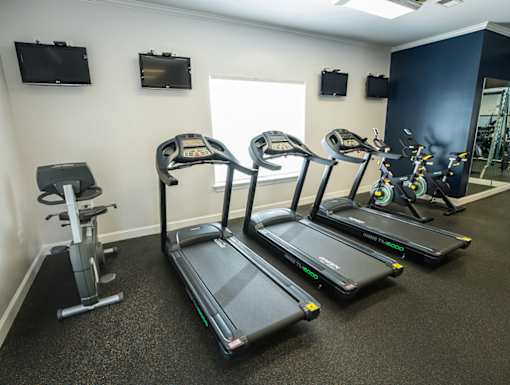 A gym with treadmills, elliptical machines, and a stationary bike.