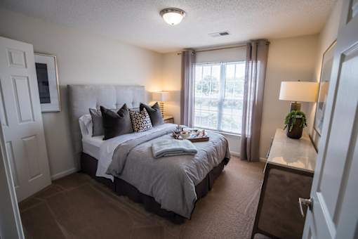 A bedroom with a large bed and a window with curtains.