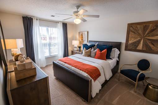 A bedroom with a bed, chair, and a ceiling fan.