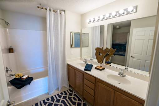 A bathroom with a white sink, a mirror, a shower, and a moose head.