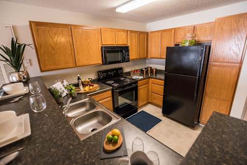 A kitchen with wooden cabinets and black appliances.